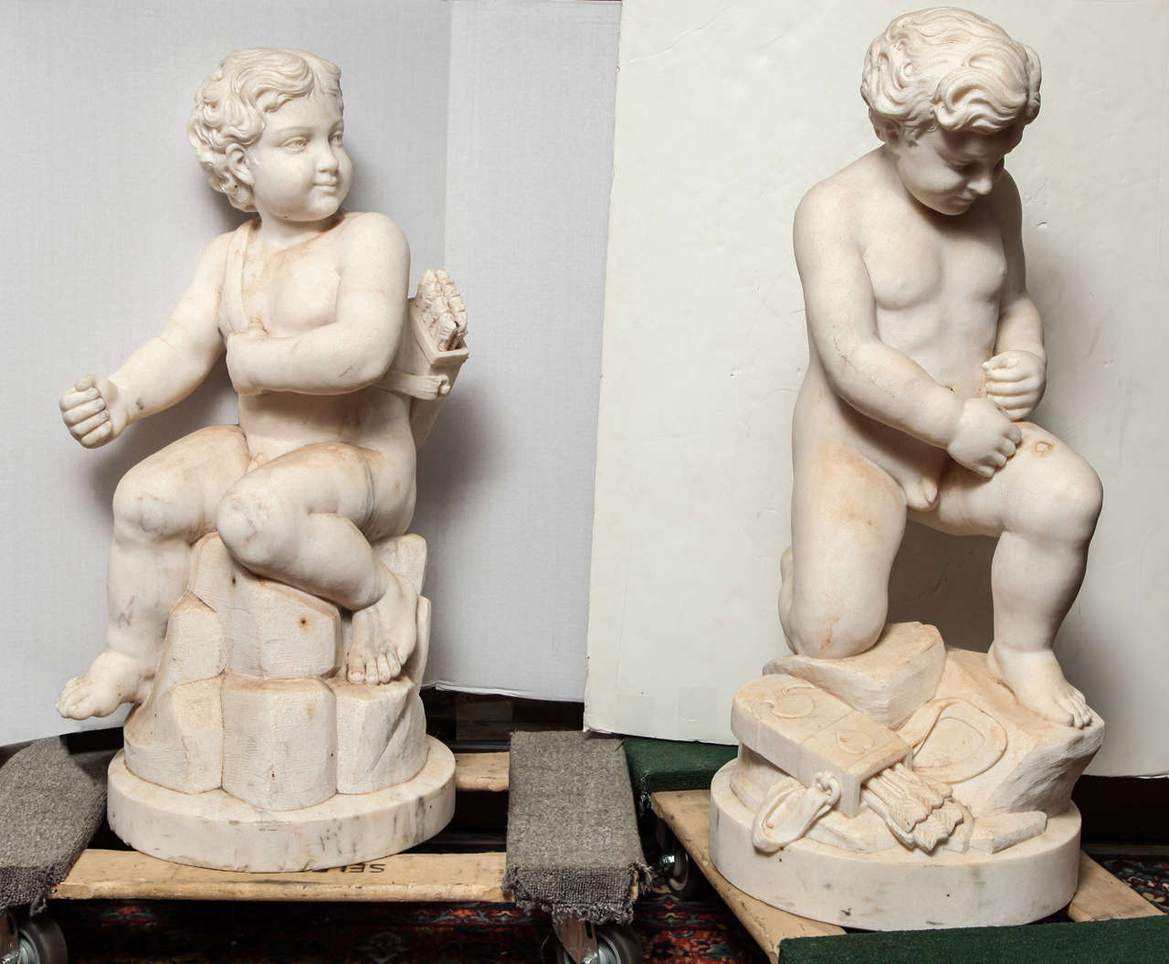 pair of Italian carved marble figures of seated cherubs in the 18th century style