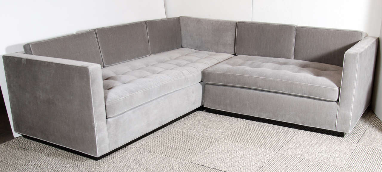 Luxe Modernist sectional sofa with biscuit tufting and formed back cushions all upholstered in a grey velvet and sitting on an ebonized walnut platform base.  This sectional is made up of two sofas, both featuring a classic high back and high arm