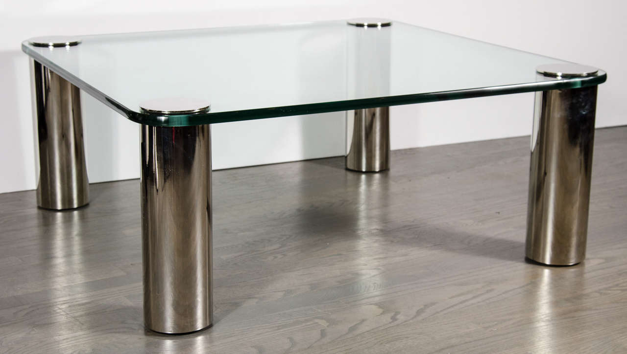 This sophisticated Mid-Century Modern cocktail table was realized in the United States circa 1970. It features a thick translucent glass top pierced through with cylindrical capped nickel legs. With its clean modernist lines, monochromatic palate