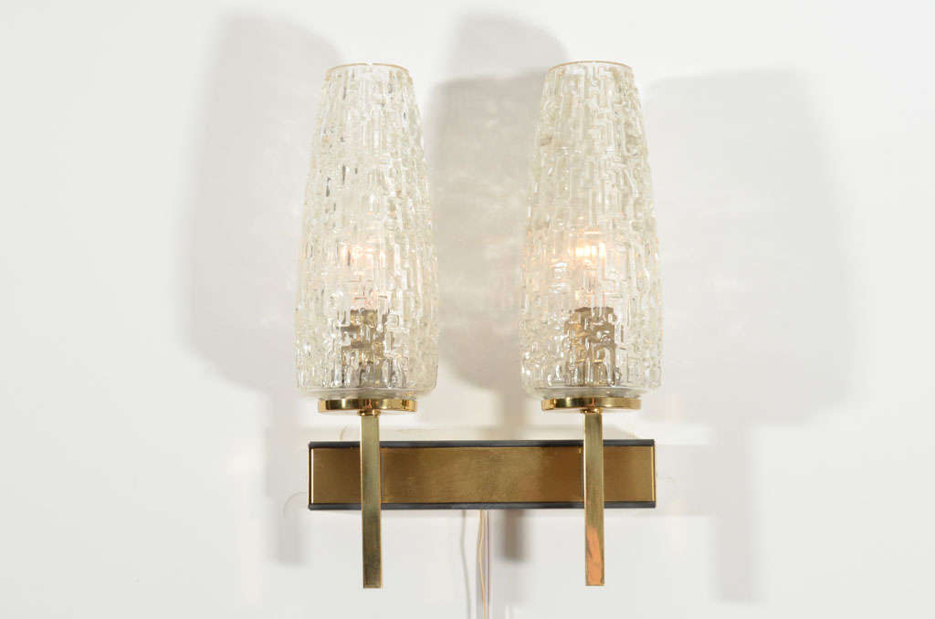 Brass two-arm wall sconce with cut glass shades.  France, circa 1960.

Beautifully made of solid brass with black edging, complemented by substantial glass sconces.

Item may be viewed at the 1stdibs@NYDC showroom at the New York Design Center,