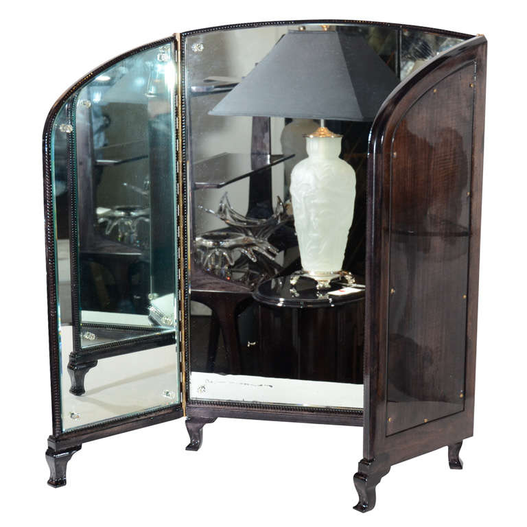 This  trifold vanity mirror has rosette details and hand beveling throughout. It is ebonized mahogany with footed cabriole style legs.