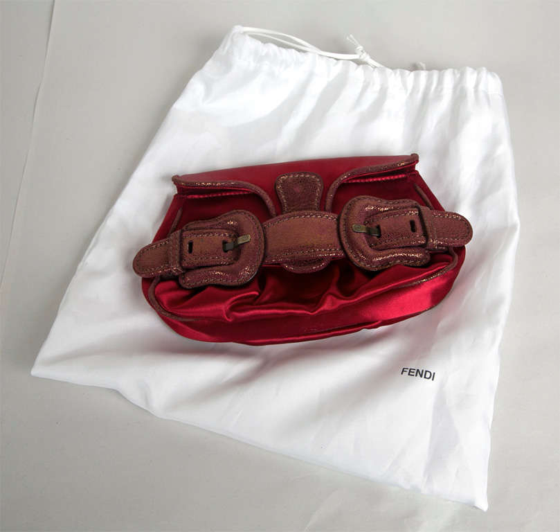 funkyfinders is sharing this sexy red satin baguette or clutch from the house of fendi. a brushed burgundy (with hints of gold) opulent leather buckle accent is fabulous. hardware is signed 'FF'. 2 delicate antiqued brass chains detach and allow for