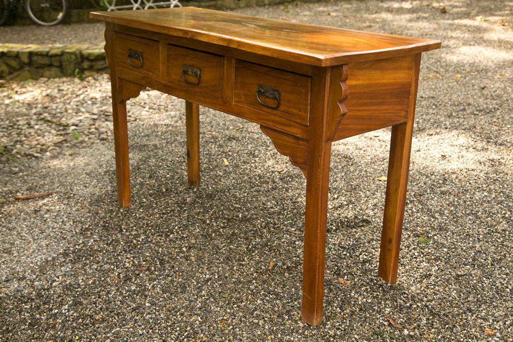 A substantial wood table with 3 drawers, each with iron pulls.