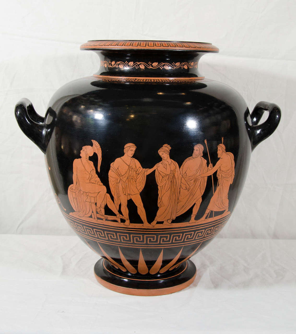 A large terra cotta Red Figure vase showing the three fates weaving the thread of life and on the reverse a seated warrior and four standing figures framed between palmettes and above a band of Greek key pattern.
The P. Ipsen factory was