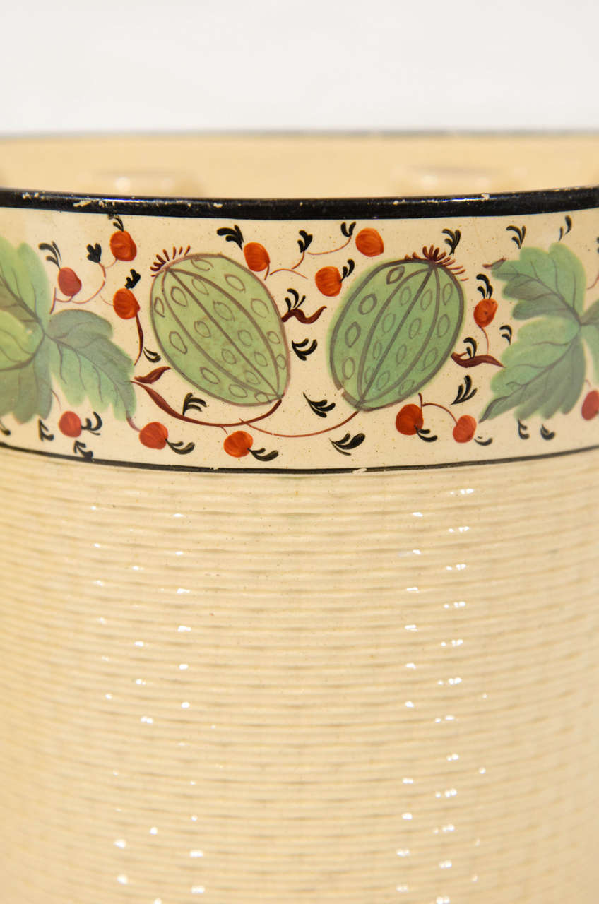 A pair of Davenport  yellowware bough pots with a molded basket weave design decorated with green leaves and red berries in a broad band across the top.
Demi-lune flat backs make these pots perfect for use on a mantle. They can also be placed back