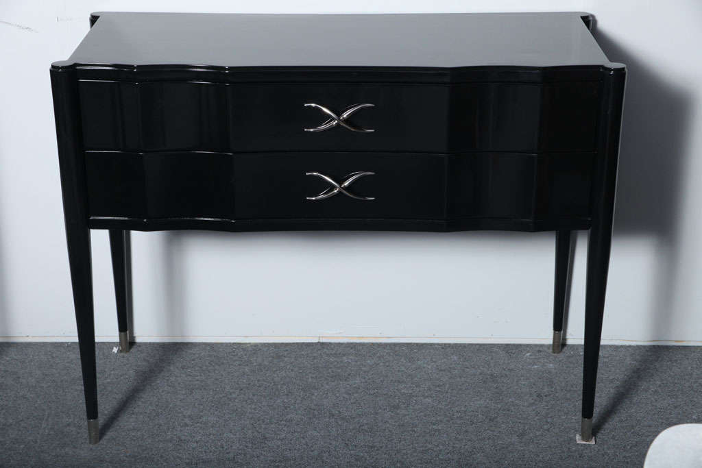 The shaped top above two conforming drawers with original nickel hardware resting on round tapering legs ending in nickel sabots.