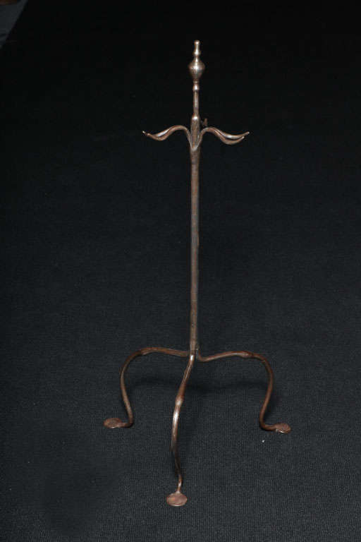 A blacksmith-made polished steel firetool stand having an elegant, sculptural design on arched legs ending in penny feet.