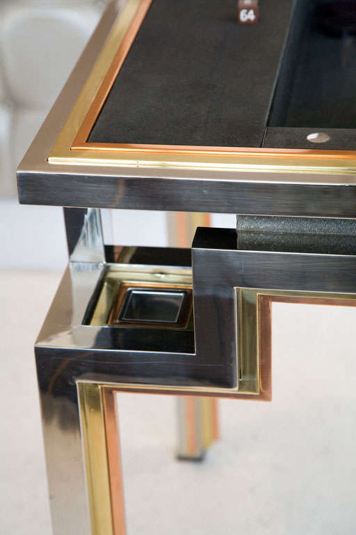 An amazing stylized backgammon (or tric-trac) table designed by Alain Delon in 1972 for The  Jansen Collection.  This game table is constructed of brass, copper and chrome with a black suede lining.  Featuring four removable ashtrays and includes