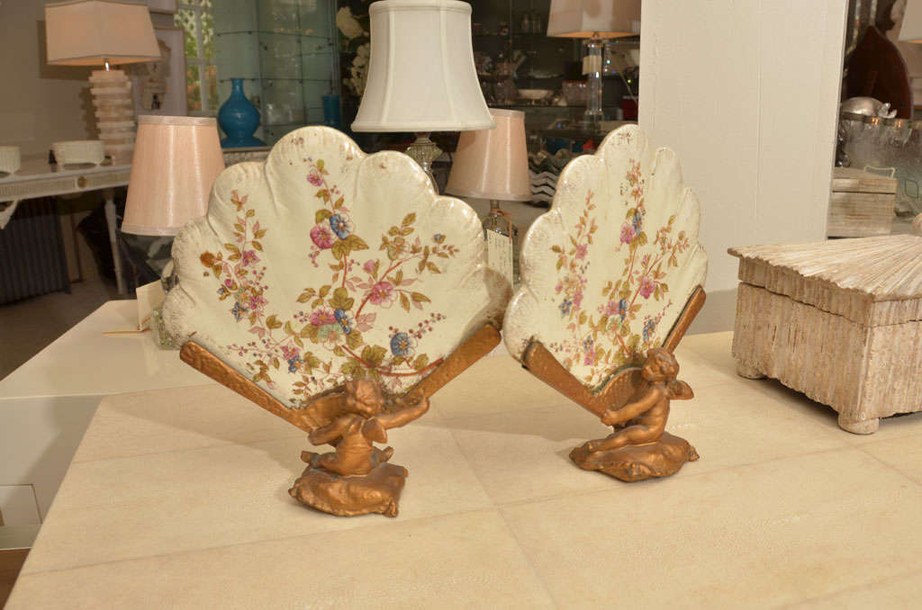 Pair of gilt metal and porcelain table screens with seated Putti's<br />
holding the painted porcelain
