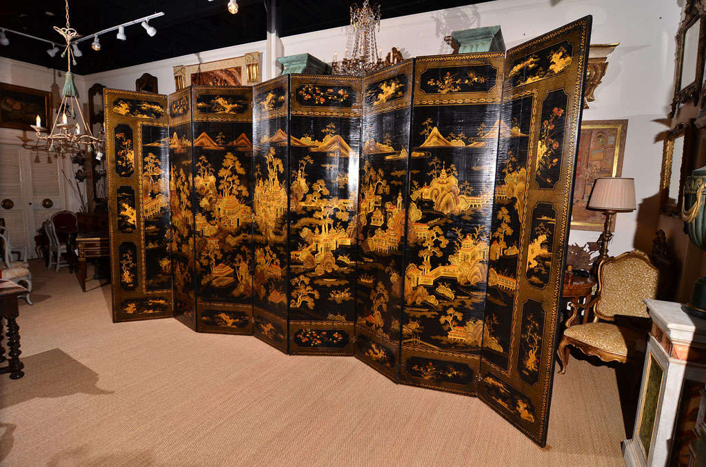 a large Chinese early 19th century eight panel screen, black lacquer with gilt chinoiserie decoration, village scenes in central body and floral designs in boxes at top and bottom.