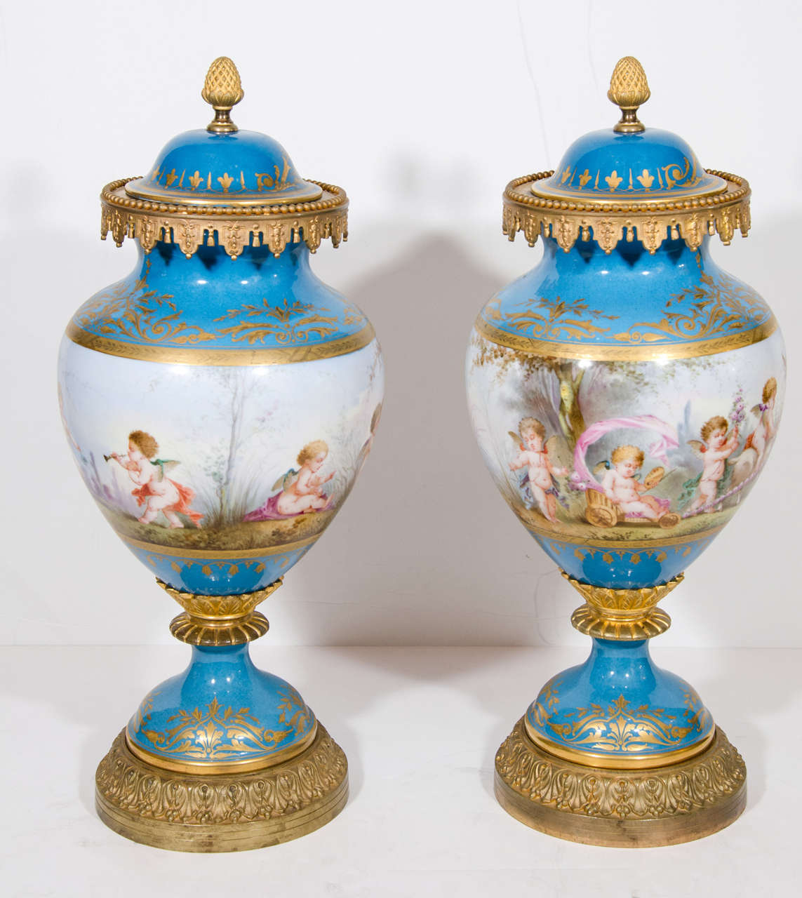 Paire de superbes vases couverts en porcelaine bleue de Sèvres de style Louis XVi, montés sur bronze doré, de belle qualité, ornés d'émaux peints à la main et de décorations dorées représentant des scènes figuratives d'enfants dans le jardin.