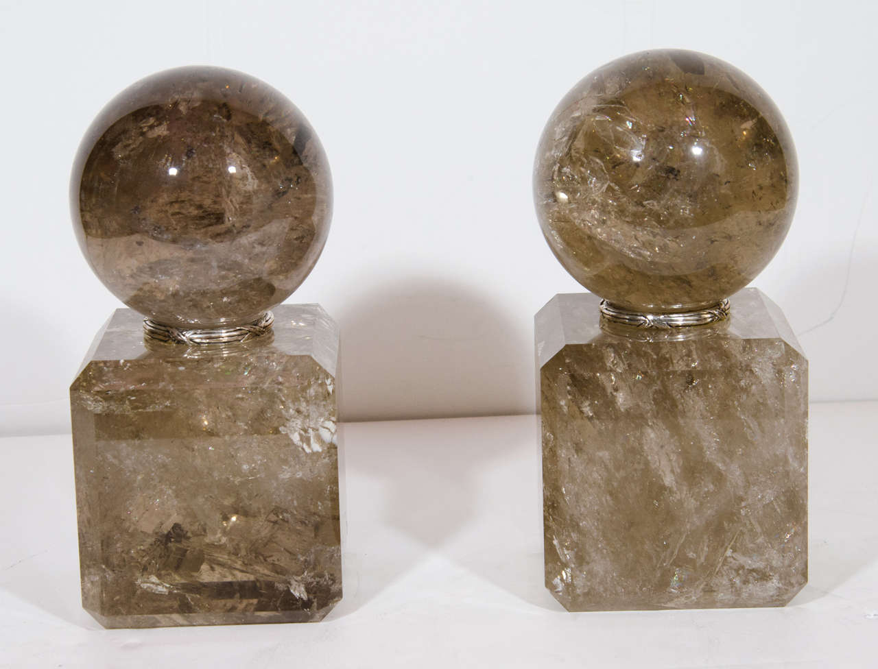 A Pair of unique Art Deco style smokey cut rock crystal silvered bronze mounted ball form decorative ornaments.