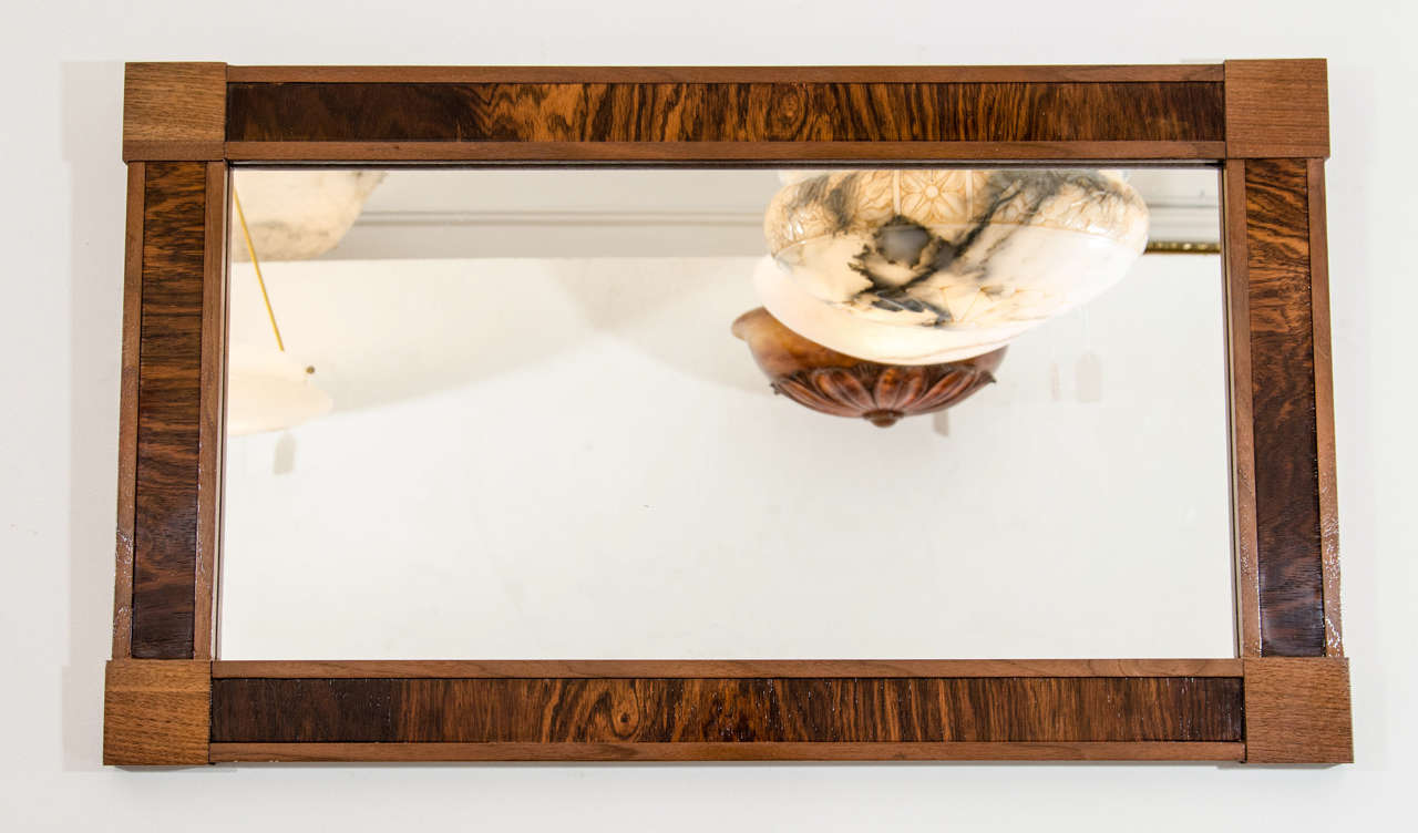 A rectangular mirror created of mahogany and French walnut panels with original glass.