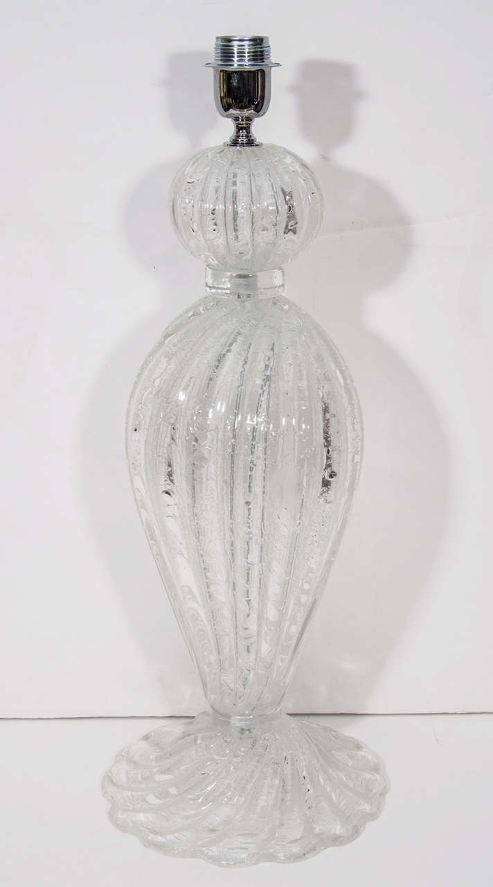 A truly spectacular pair of table lamps in clear Murano glass.  The lamps have a sculptural form wonderful bubble effects throughout and a beautiful scalloped base. The height is to the top of the socket.