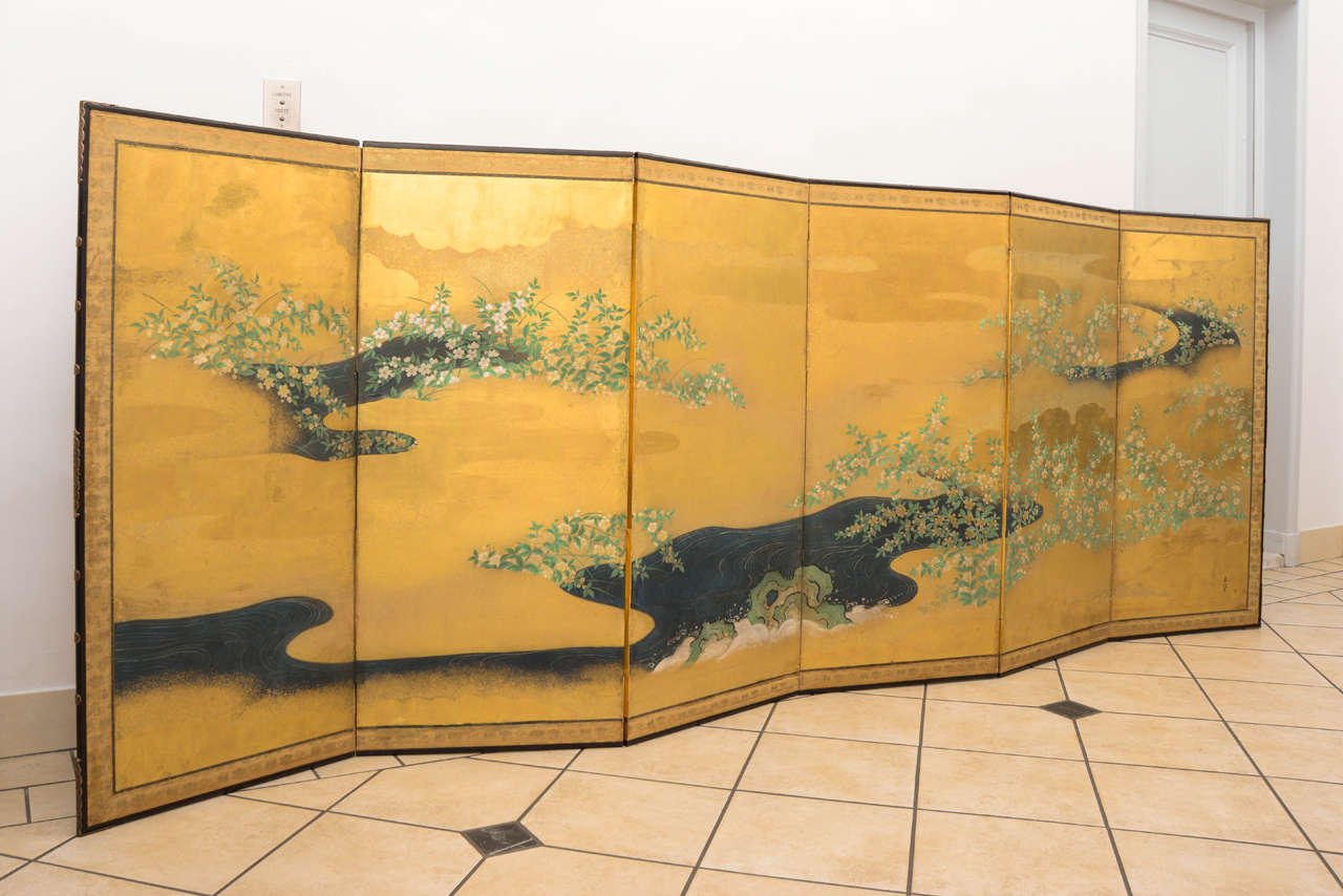 Beautiful six leaves screen with a golden background decorated with flowering branches in a river running landscape. 
It bears the signature of Minenobu Kano (1668-1708).
