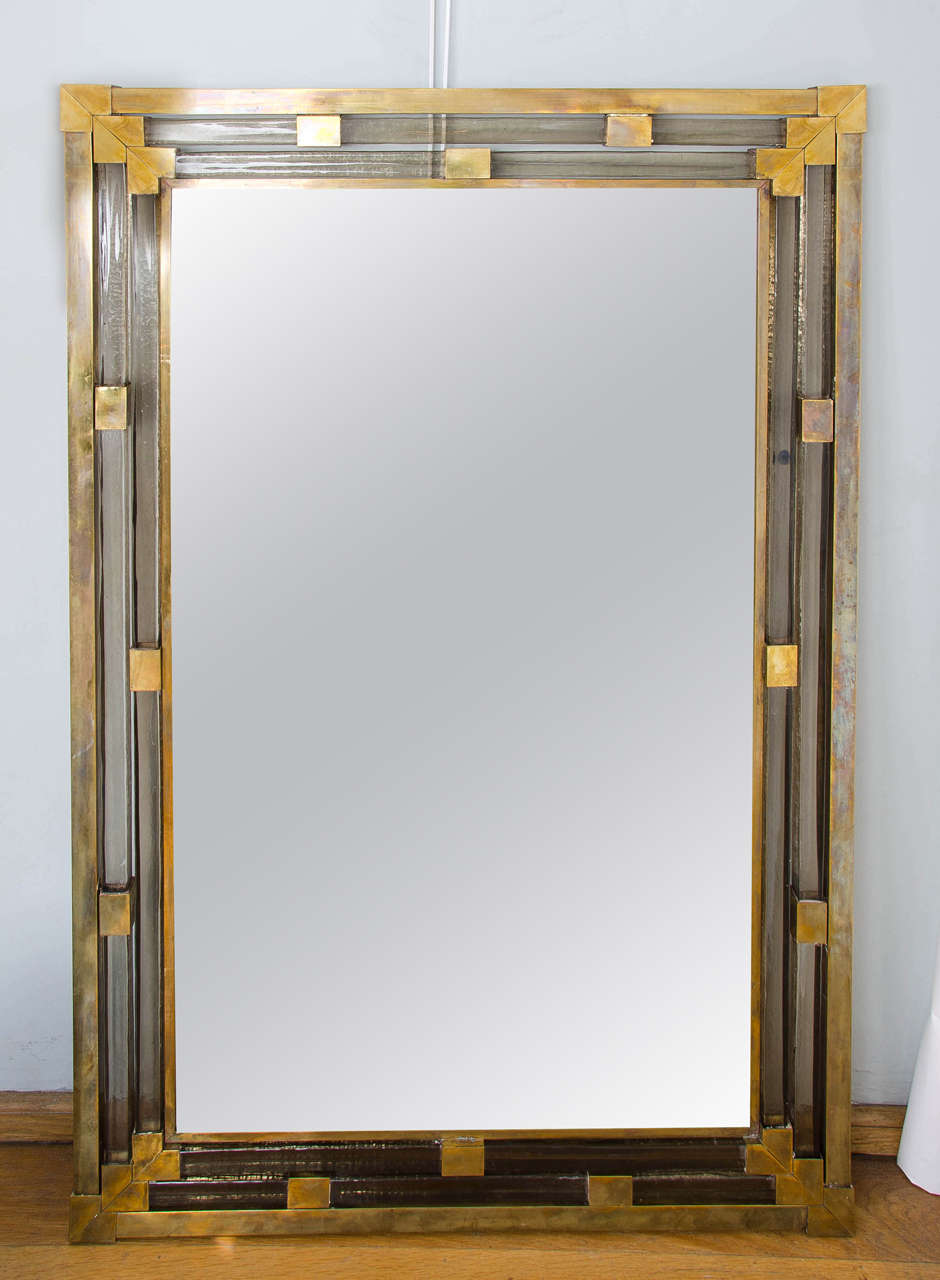 Mirror encased by four layers of thick brass and subtle smoky glass interspersed with solid cubes with triple brass corners. Classic with a twist.