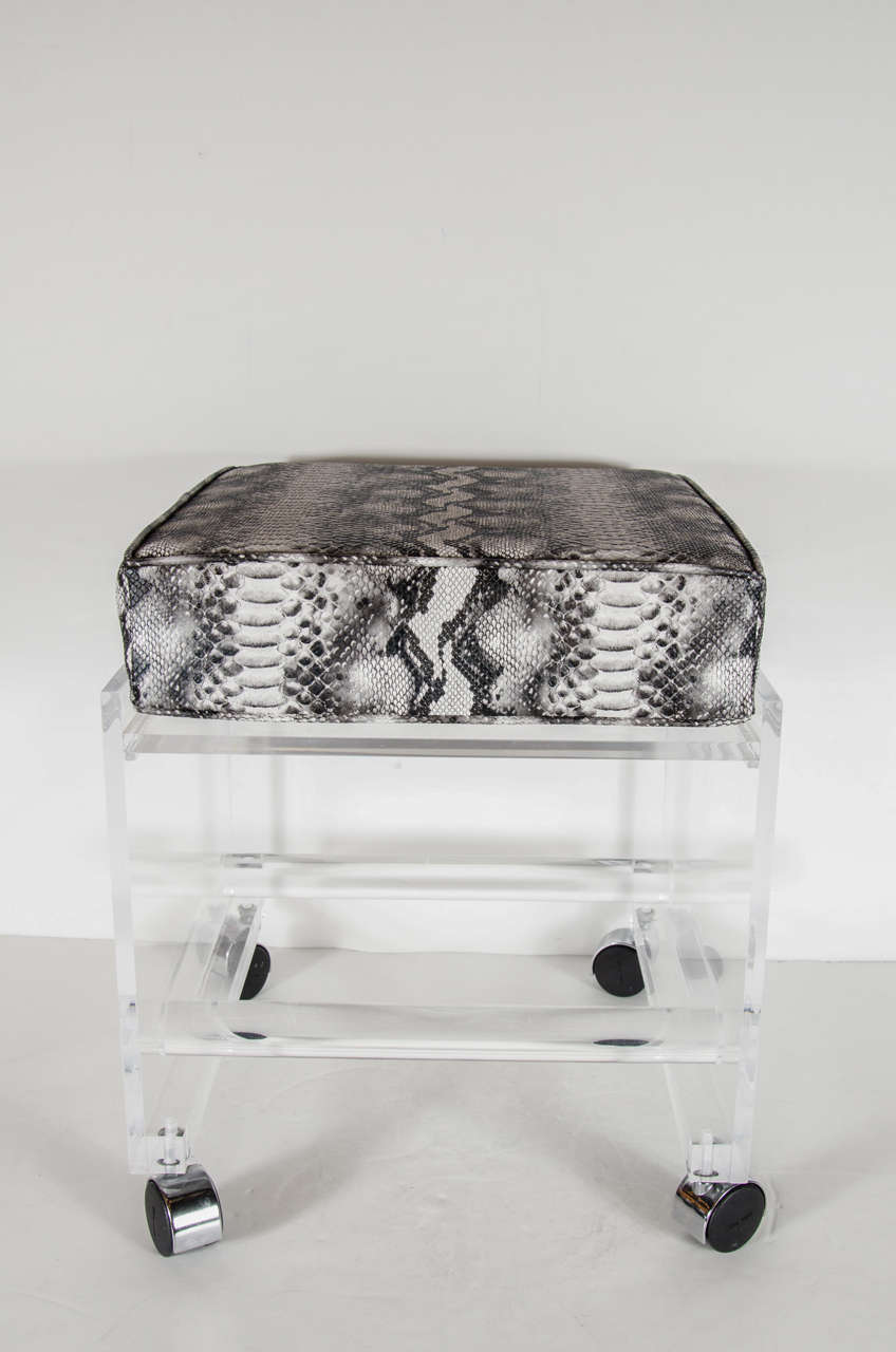 This chic Mid-Century Modernist Lucite stool features an open cube-like form with castors with chrome covers, two thick Lucite support rods and a comfortable seat newly upholstered in black and white faux python. 

American, Circa
