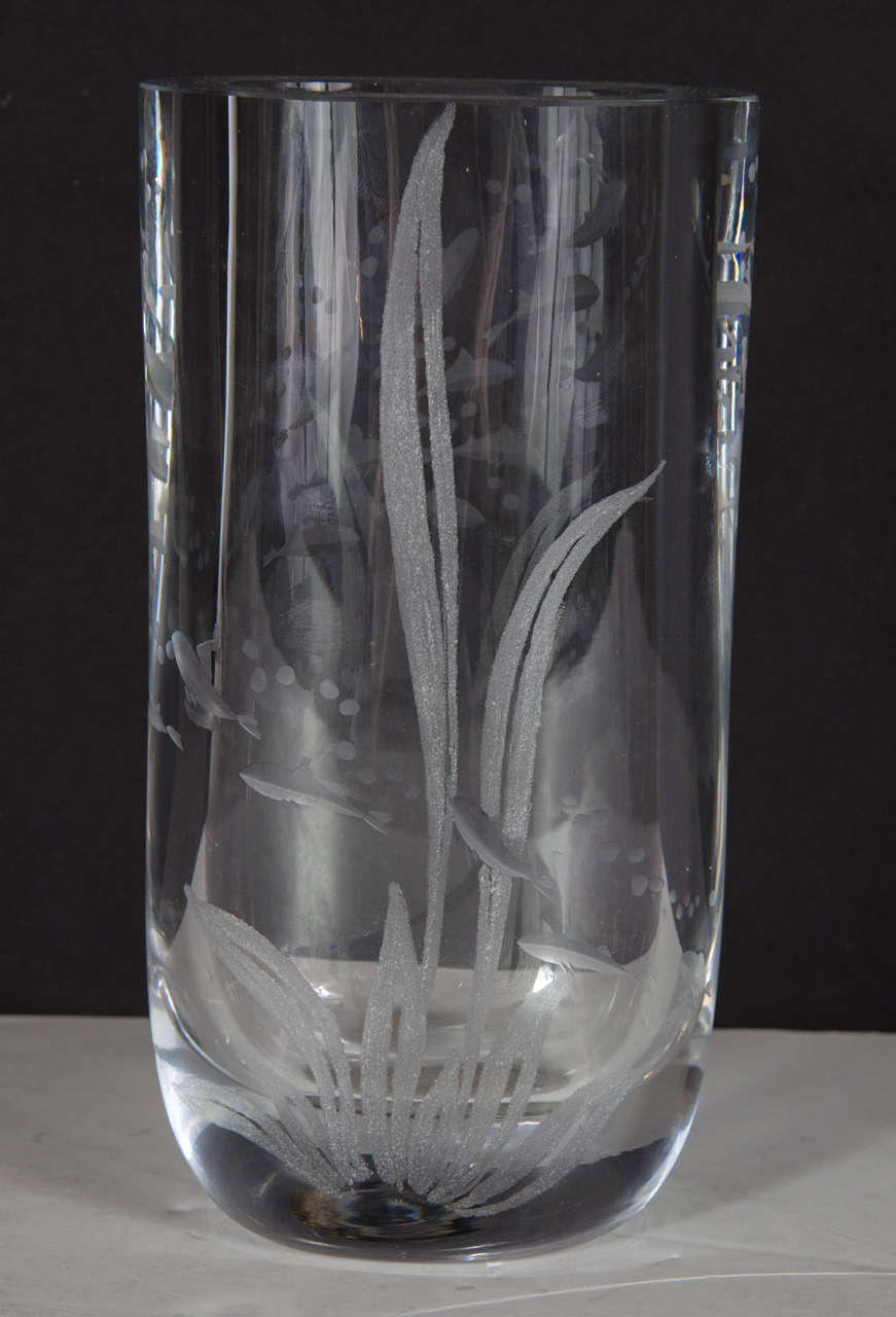 This oblong cylindrical form vase features hand etched stylized fish swimming with bubbles and stylized sea grass. It is signed Kosta, Sweden on the bottom as well. Great as a decorative object or very functional as a vase.