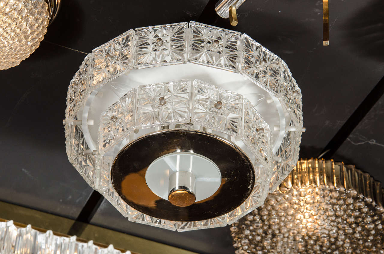 This gorgeous Mid-Century Modernist flush mounted chandelier by Kinkeldey consists of numerous panels of deep faceted crystal fixed to a two tiered circular chrome frame. The frame supports seven candelabra bulbs and has been newly rewired. This
