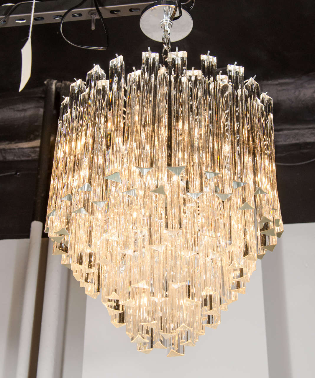 This exceptional Mid-Century Modernist Camer chandelier features individually handblown Murano glass triedre prisms that hang from its chrome frame in a cascading effect. The high quality glass reflects the light beautifully for added dimension and