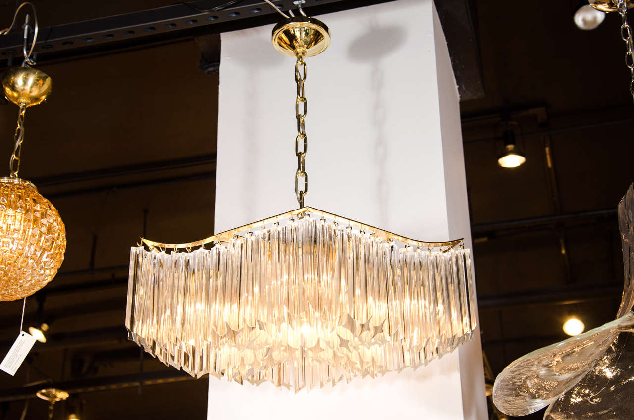 This sophisticated Mid-Century Modern pagoda chandelier was realized in Italy, circa 1970. It features an abundance of Camer chandelier consists of clear quadretti crystals suspended from a brass frame. When viewed from beneath the fixture's crystal