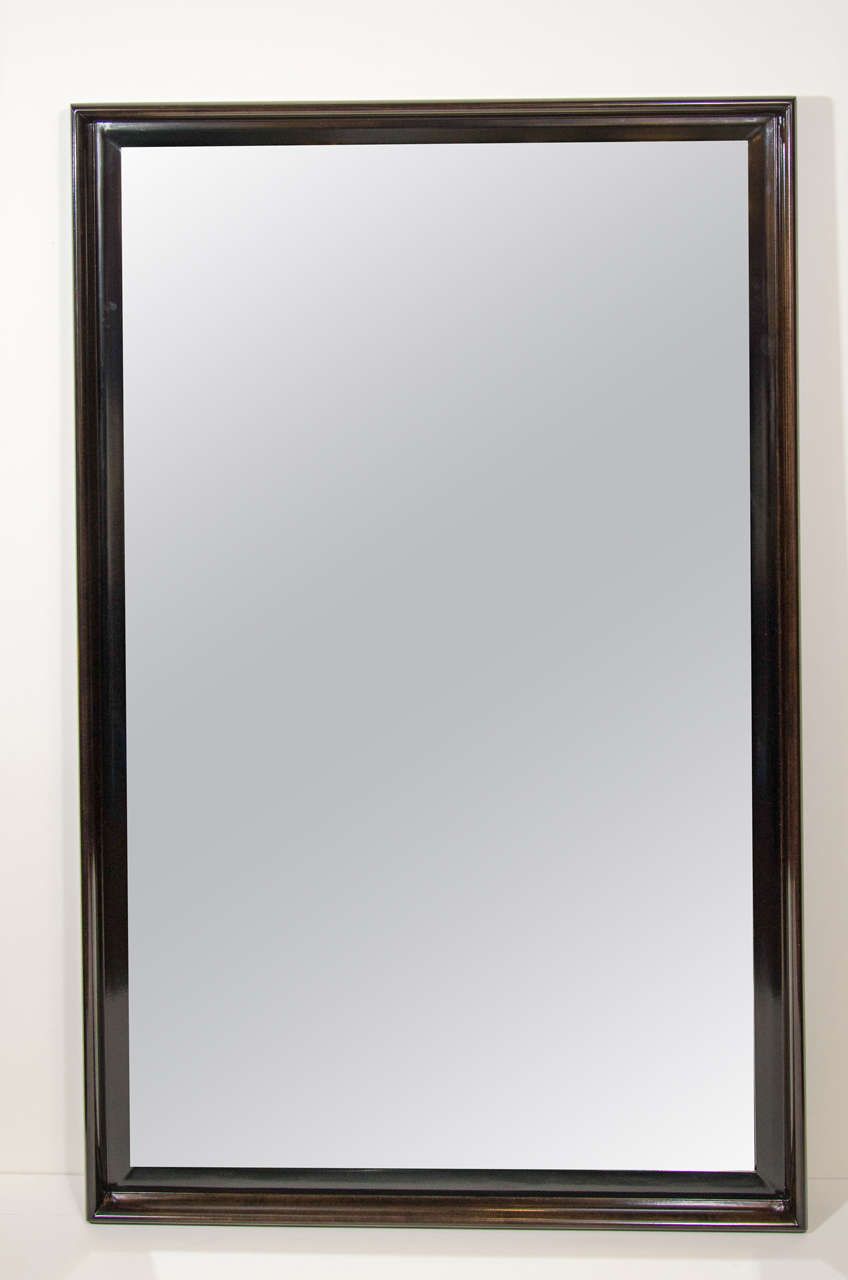 Handsome mid century mirror designed by Paul Frankl for John Stuart Inc..  The mirror has a streamline shadowbox design and has been newly refinished in dark mahogany with satin black lacquered interior trim.  Matching high chest available and sold