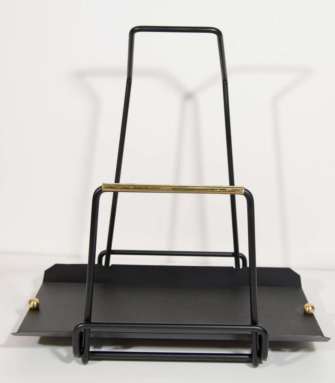 Mid-Century Modern log holder or magazine stand in the manner of Mathieu Matègot. Black enameled iron with brass trim and brass ball accents.