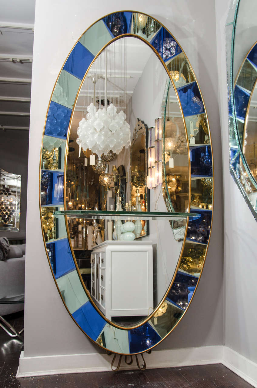 Crystal Arte oval standing mirror with beveled cobalt glass frame surrounding mirrored panels.