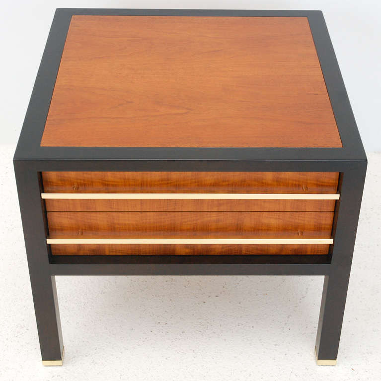 A handsome two-drawer wood side table with an ebonized frame, caned bottom shelf and brass drawer pulls and sabots. Retains the Baker emblem inside the drawer (see Image 5).