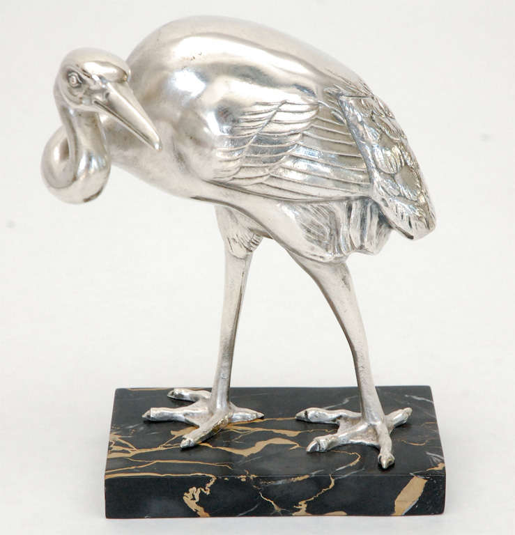 A detailed silver plate rendering of an egret on a veined marble base.  Artist signature to the marble base.