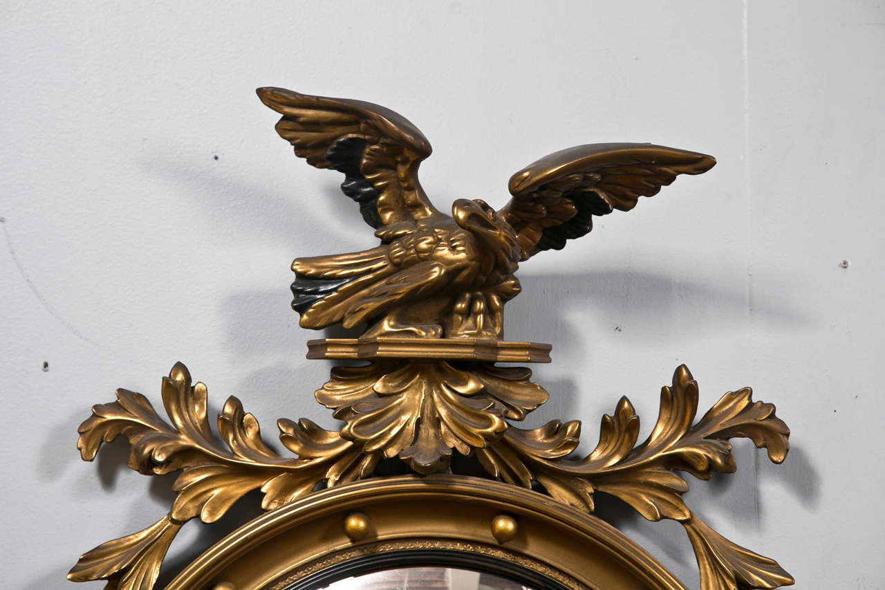 Pair of American Federal style wall mirrors, early 20th century, each has a circular bulls'eye mirror surmounted in a beveled and beaded gilt frame, the top decorated with eagle and foliate crest, similar design at the bottom.