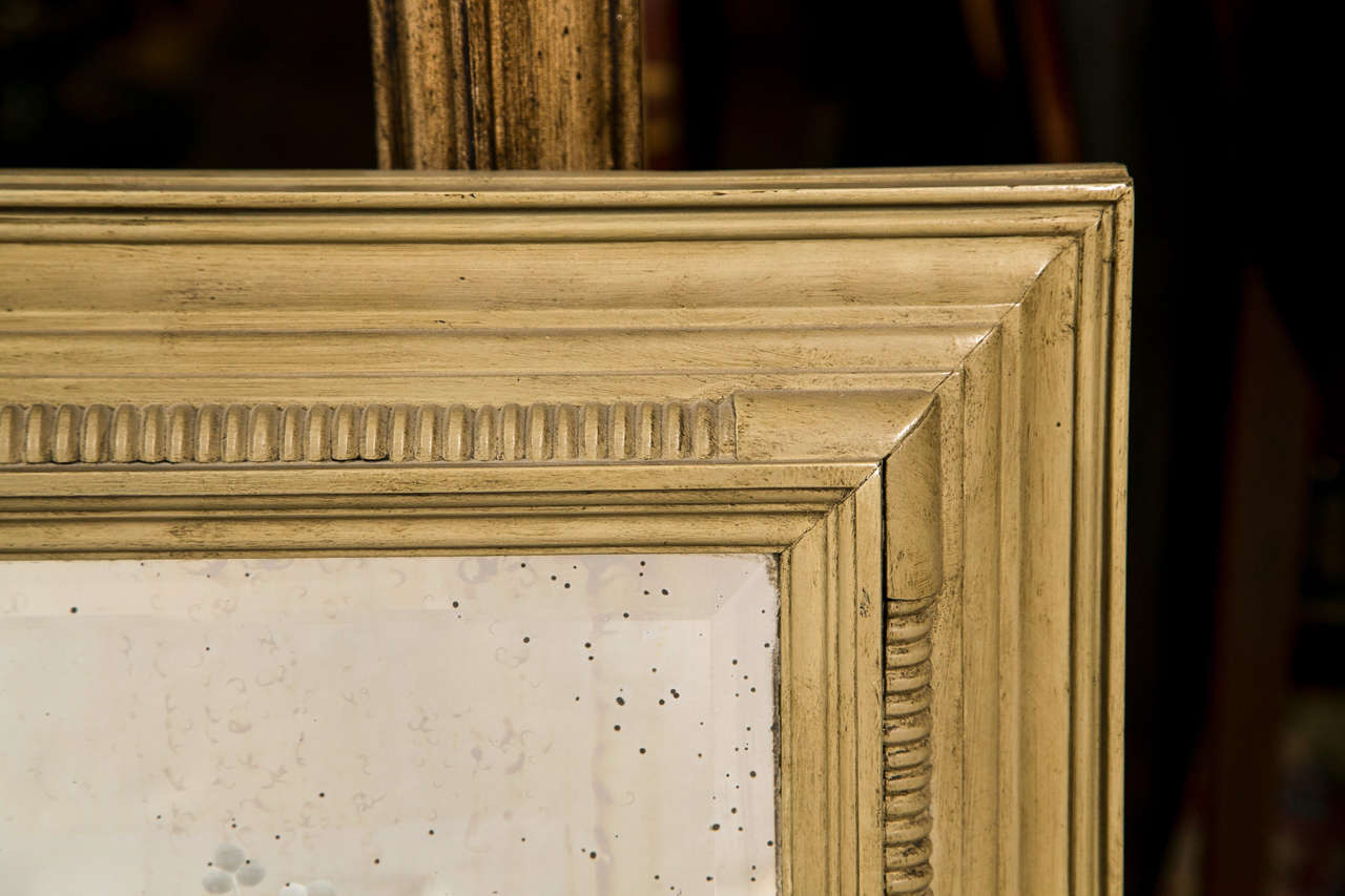 An decorative mirror with beautiful etching of an urn and flower arrangement, framed in this distress beige painted wood frame.