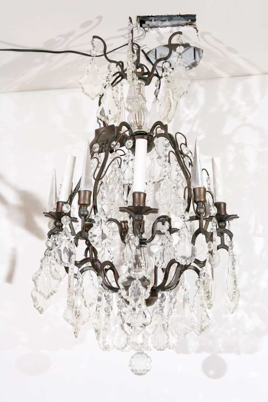An elegant French cut crystal chandelier. Frame is bronze and the piece is decorated with hand cut and beveled lead crystal drops and finials. Has 5 light sockets. Fixture itself is 26 1/2
