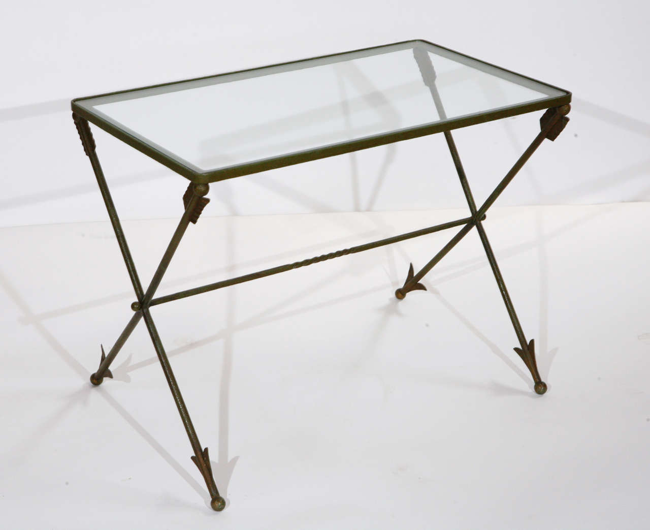 A vintage Italian green patinated metal arrows table so popular during the Hollywood Regency period. It has a X base design and has a new glass top. This table was purchased in Holland in the 1970s but most likely is Italian made. This would make a