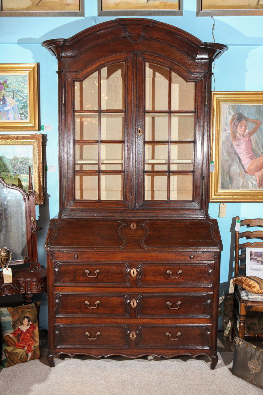 An early 20th century French Regence style two-part secretaire originally purchased in Paris, France. The secretary has a slant front desk section that rest on two sliding pulls. Interior has six drawers with hand-carved wood pulls. Lower cabinet