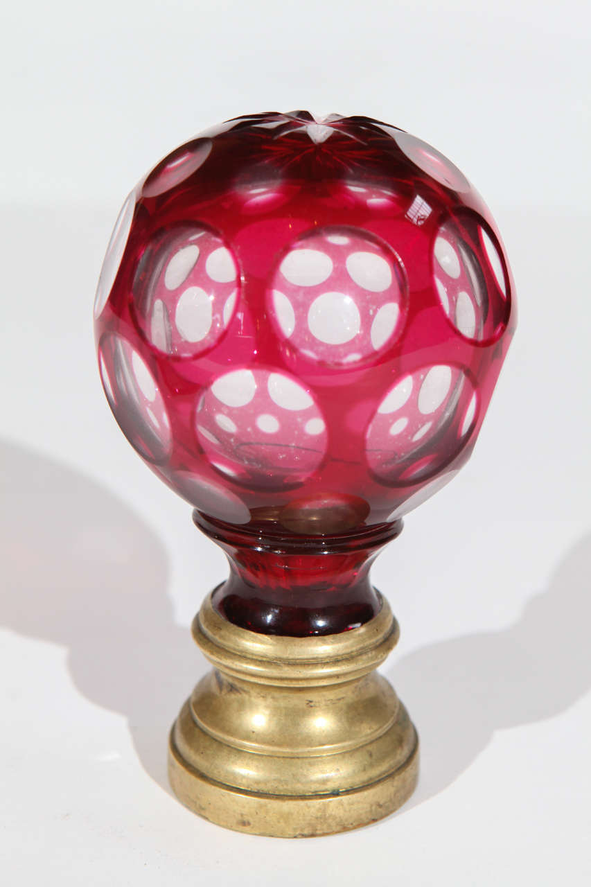 An amazing early 20th century crystal St Louis staircase finial. Made of faceted cranberry glass mounted on a brass base. Decorated with a cut designed star on top. Facets create the illusion of a webbed design when looking through the finial.