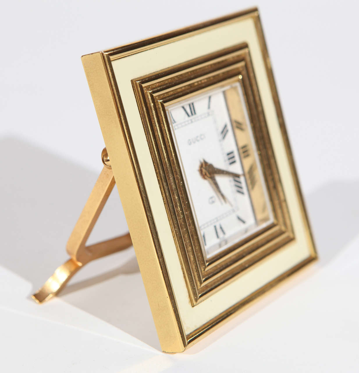 An elegant mid century Swiss made Gucci clock. Made of solid brass and cream colored enamel. Please note that one of the knobs that sets the alarm is missing on the back.