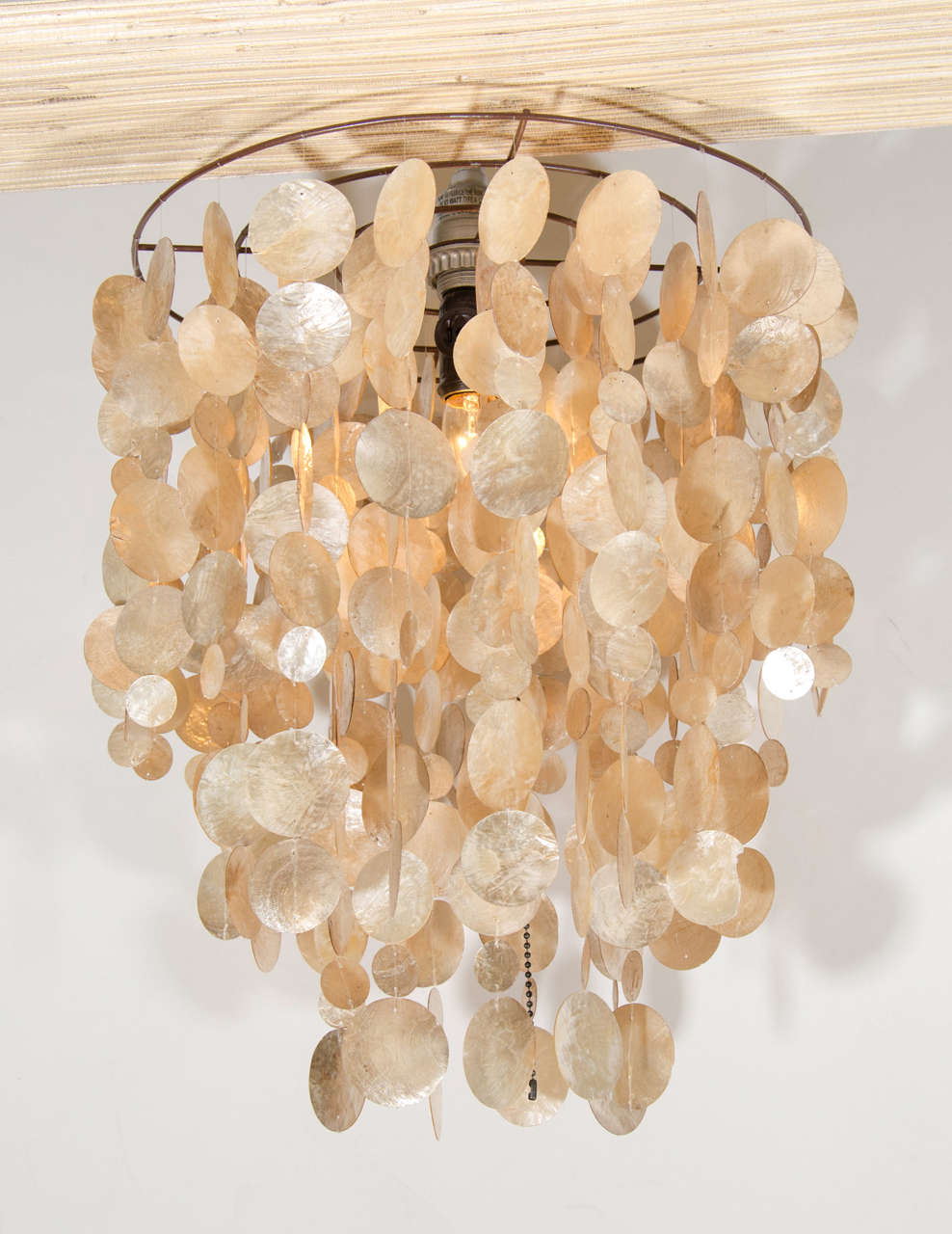 A vintage iridescent capiz shell chandelier with descending concentric circles.

Good vintage condition with age appropriate wear. Several shells are chipped.