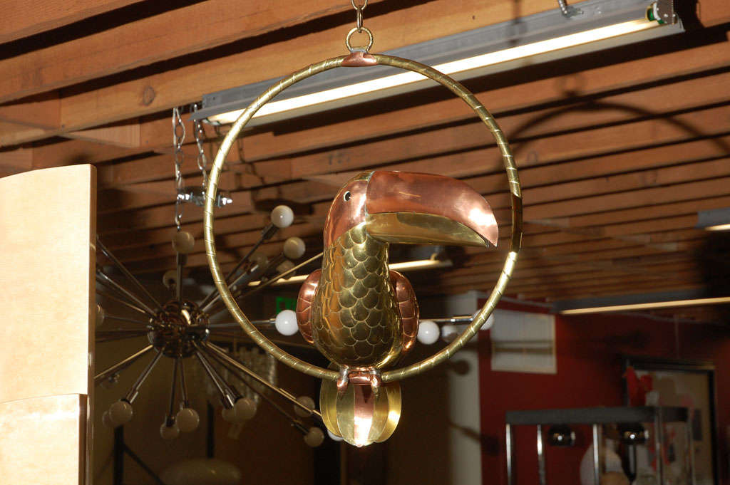 Lifesize brass and copper Sergio Bustamante Folk Art Toucan parrot on swing.
Please note: Dimension provided is parrot only

Though born in Culiacan, Sinaloa, Mexico, Sergio Bustamante has lived in the Guadalajara area since early childhood. In his