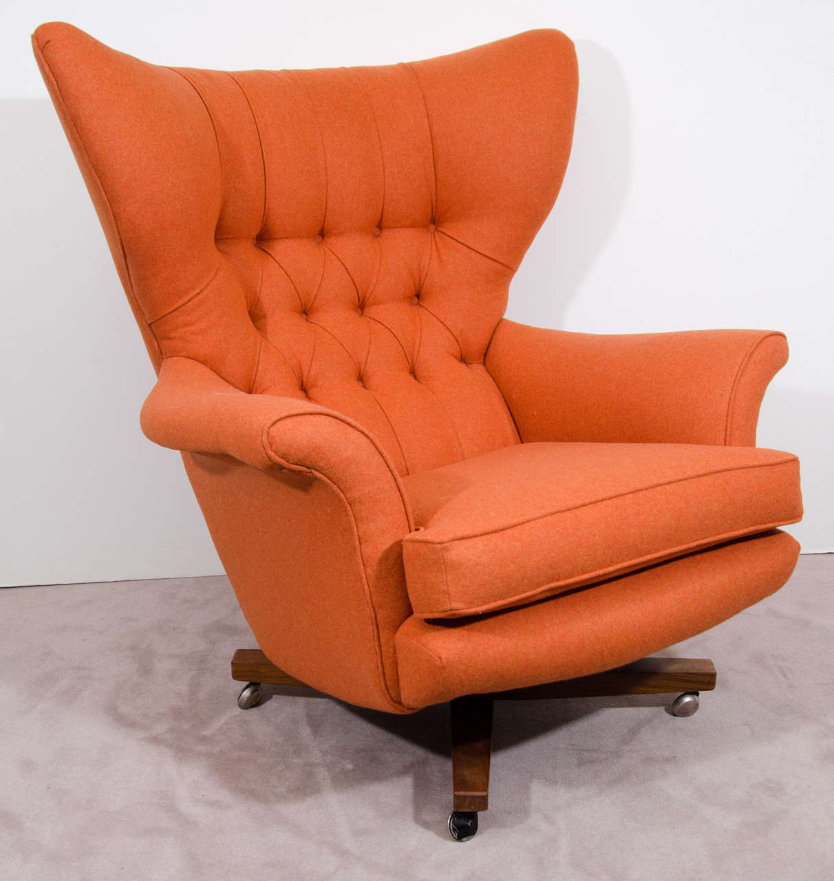 A vintage high back 6250 lounge chair by Paul Conti for G-Plan. The piece has button tufted cushions recently reupholstered in orange Italian wool and a rosewood swivel base with casters.

Reduced from:  $3800