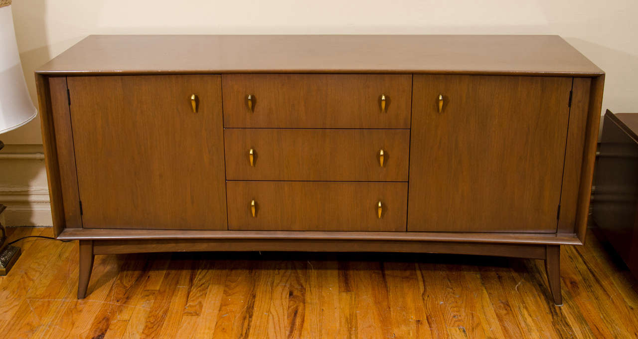 A vintage sideboard with three central drawers, two side cabinets with adjustable shelves and brass tear-drop shaped pulls. The piece is by Russell Spanner for Ruspan.

Reduced from: $3000