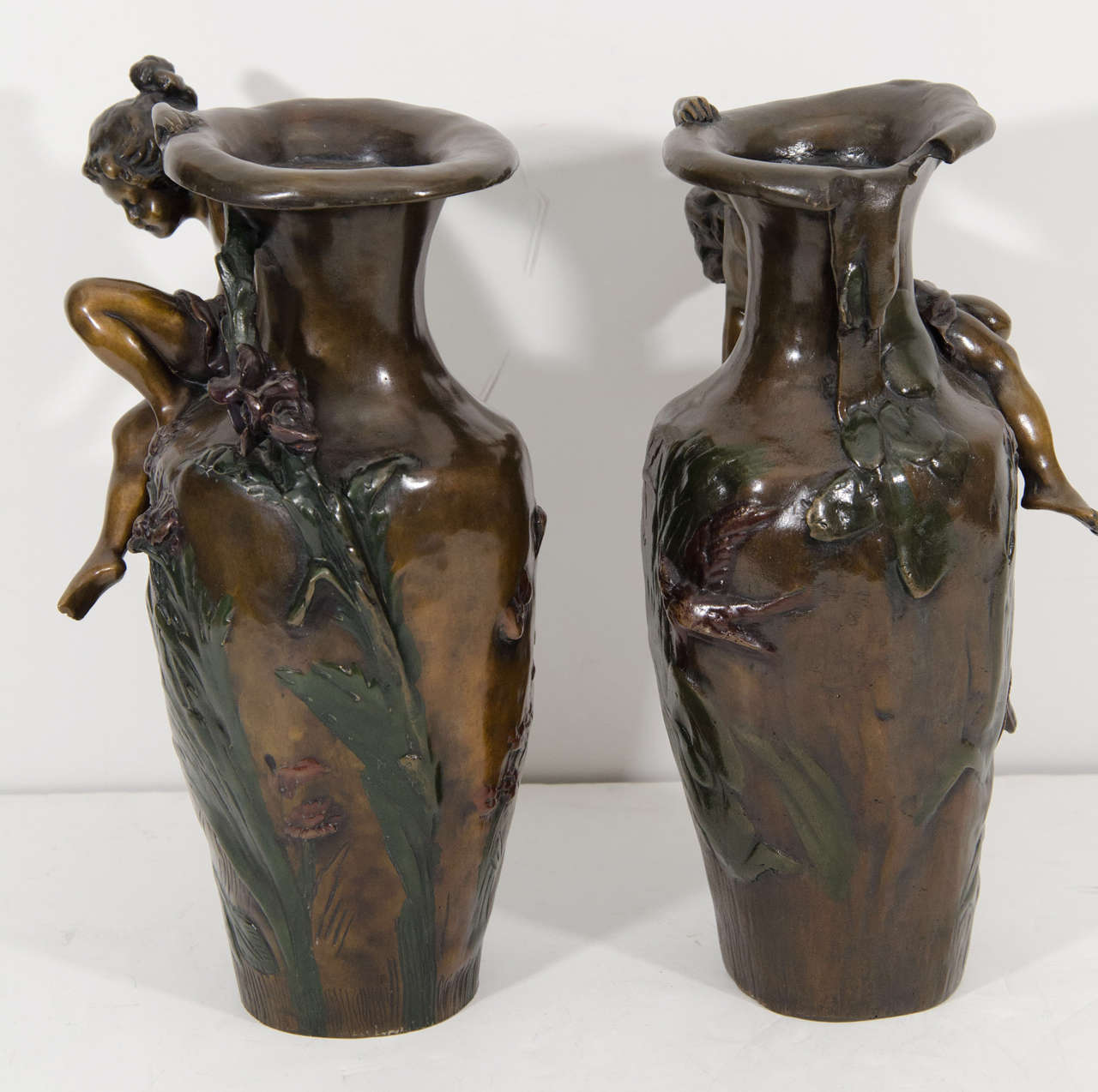 A pair of bronze vases with raised dragonflies, foliage and cherub Figures. Signed Auguste Moreau