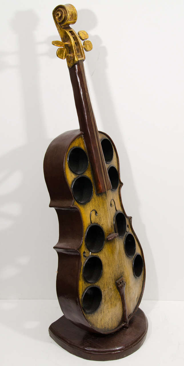 A cello shaped wine bottle rack in carved wood and gesso with ten slots.