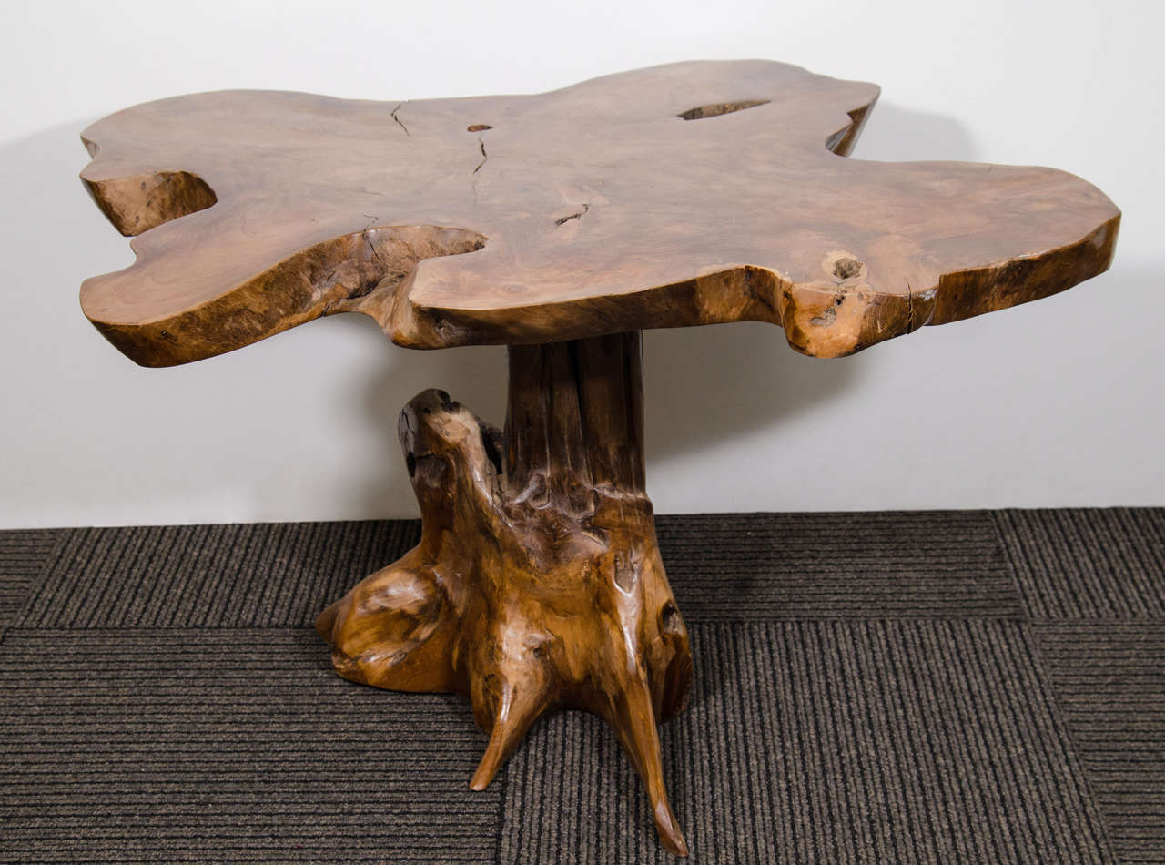 A vintage side table made from a tree root with a live edge organic surface.