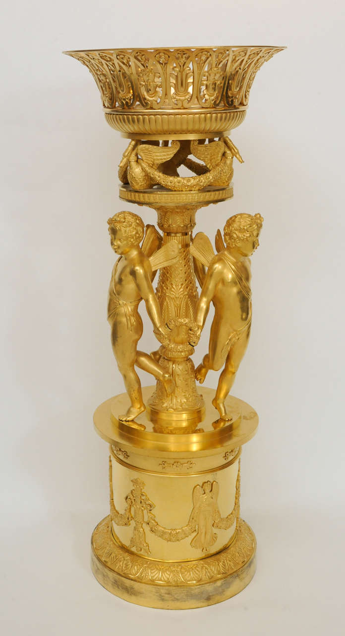 A magnificent Empire gilt bronze figural centrepiece attributed to the pre-eminent bronzier Pierre-Philippe Thomire, with a pierced basket above three supporting winged cherubs.

Intended to hold flowers or fruit, this wonderful centrepiece formed