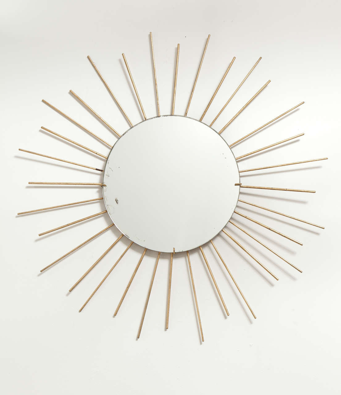 Large brass starburst wall mirror, France, circa 1960. Features a round mirror with invisible frame and brass rods in alternating lengths.  

Dimensions:
28 inches in diameter.
12 inch mirror diameter.