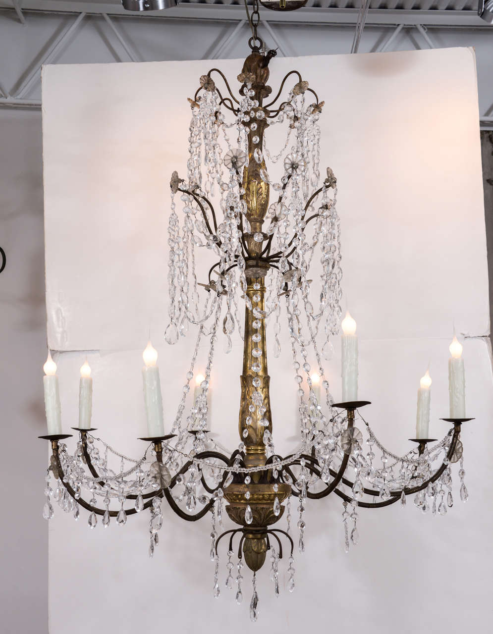 Large early 19th century three-tier chandelier from Genoa, with a carved wooden body with remnants of original gilding and eight iron arms, with crystal flower motifs, draped in clear glass bead chains with suspended crystal pendants. This