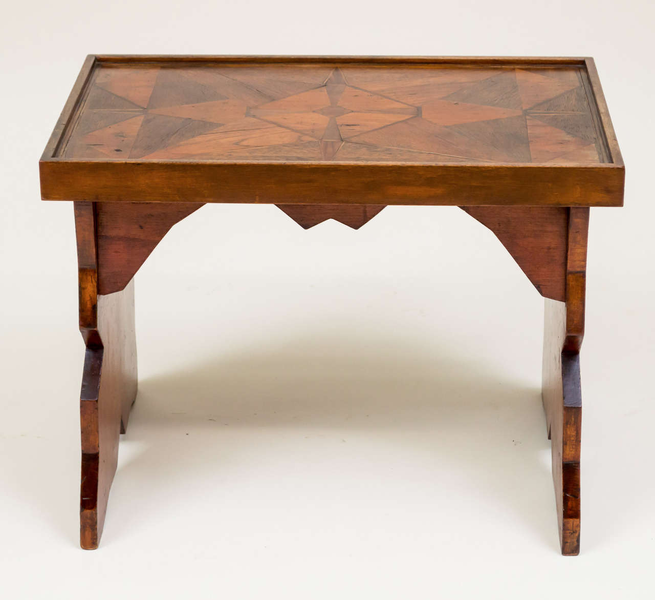American folk art low coffee table of good scale. Stylized Deco form with geometric marquetry top. Old varnish finish brought up with wax.