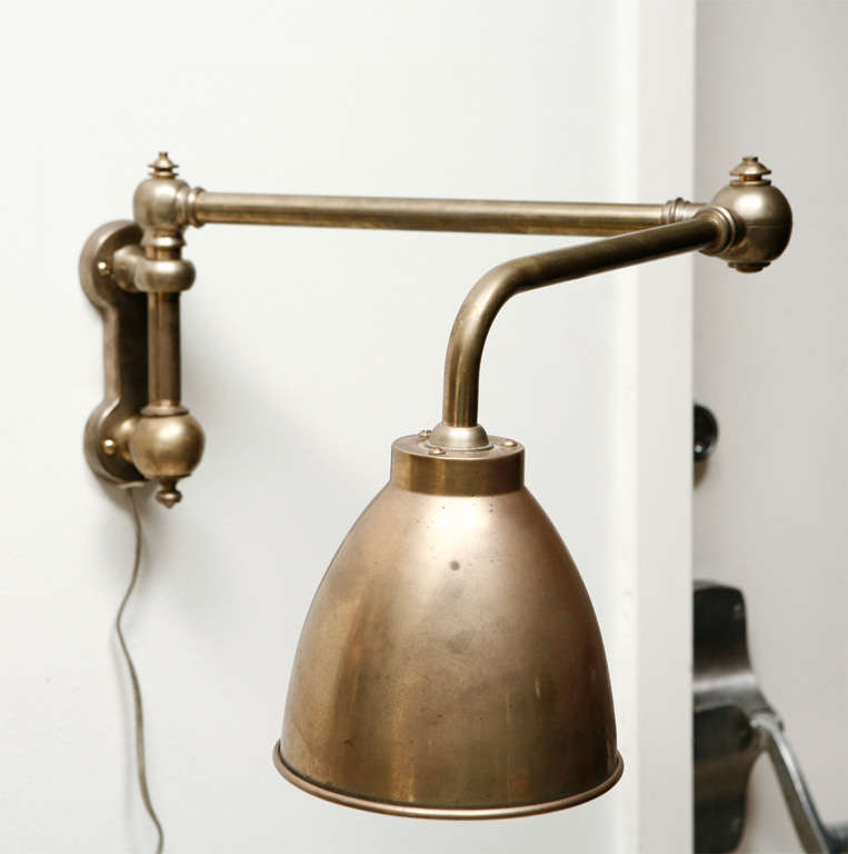 Adjustable brass swing-arm reading sconce.  Pivots on two joints.  Hood measures 6
