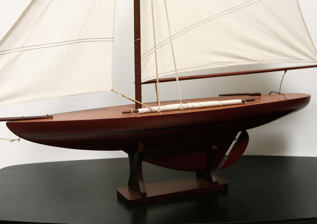 Sleek wood model of a large sailboat.